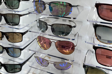 The image displays a collection of sunglasses with various designs and colors, displayed in a clear case for sale.