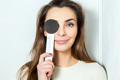 The image shows a woman holding a thermometer to her forehead, with a black and white filter applied.