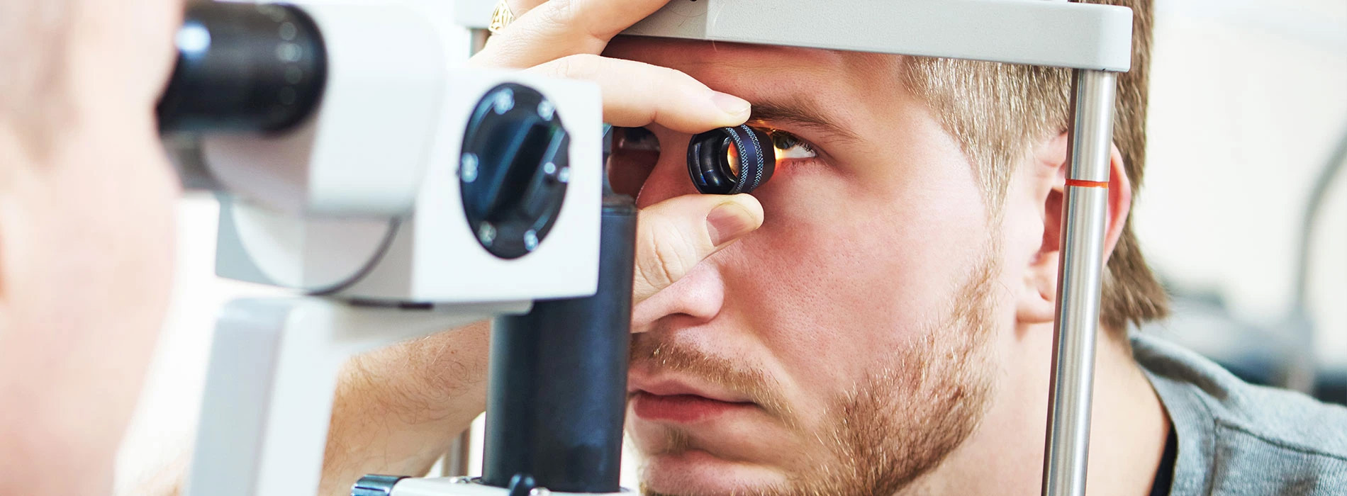 The image shows a person sitting in front of an eye exam machine, with a focus on their eyes and the device they are using.