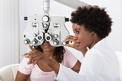 The image shows a scene where an optometrist is performing an eye examination on a patient.